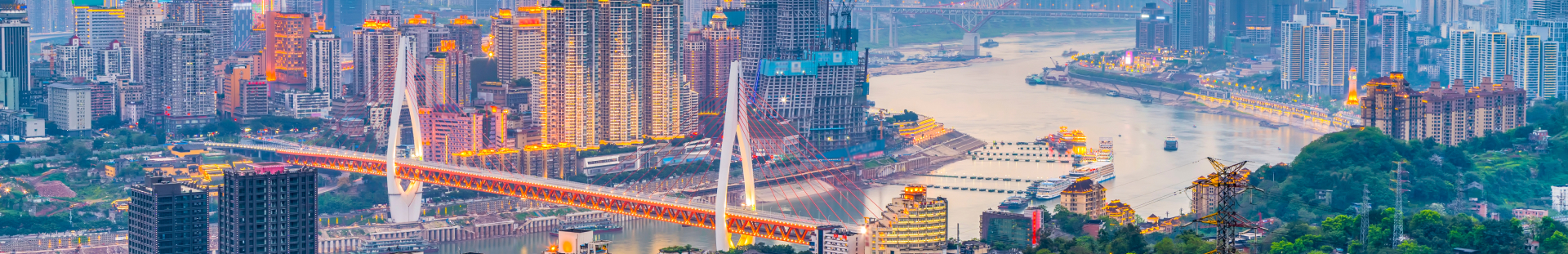 Skyline of a vibrant city at sunset, featuring a river with illuminated buildings along the banks